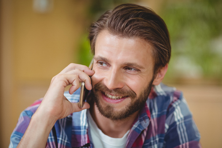 Close-up of male executive talking on mobile phone in officeの写真素材