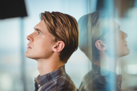 Thoughtful executive standing in officeの写真素材