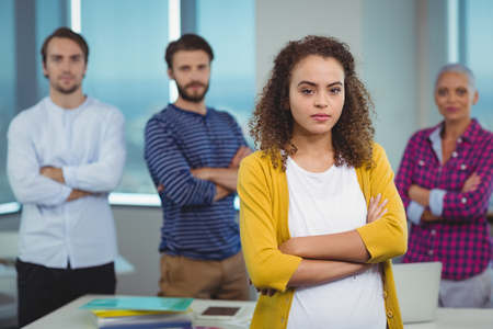 Portrait of executive standing with her colleagues in background in officeの写真素材