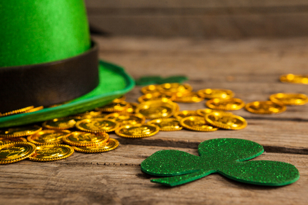 St Patricks Day leprechaun hat with shamrock and gold chocolate coin on wooden backgroundの写真素材