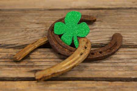 St Patricks Day shamrock with two horseshoes on wooden tableの写真素材