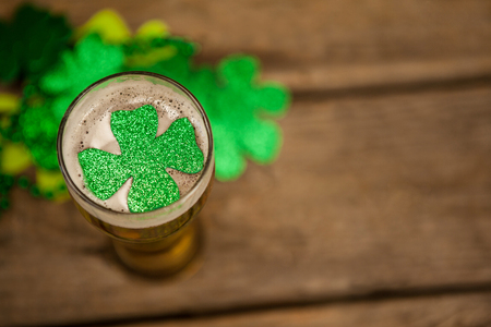 Glass of beer and shamrock for St Patricks Day against wooden backgroundの写真素材