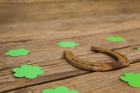 St Patricks Day horseshoe surrounded with shamrocks on wooden table