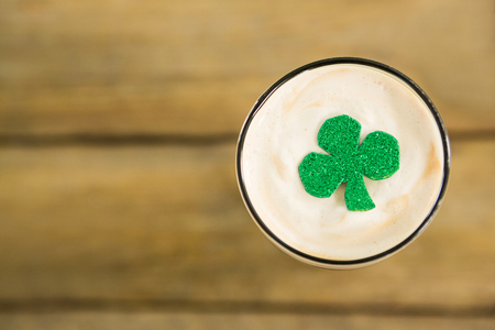 St Patricks Day glass of beer with shamrock on wooden surfaceの写真素材