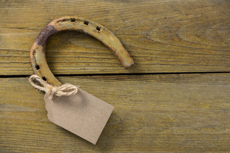 Close-up of horseshoe with empty tag on wooden surfaceの写真素材