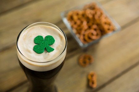 St Patricks Day glass of beer with shamrock on wooden surfaceの写真素材