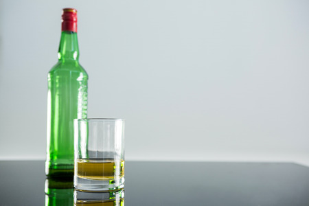 Whiskey bottle and glass kept on table against white backgroundの写真素材