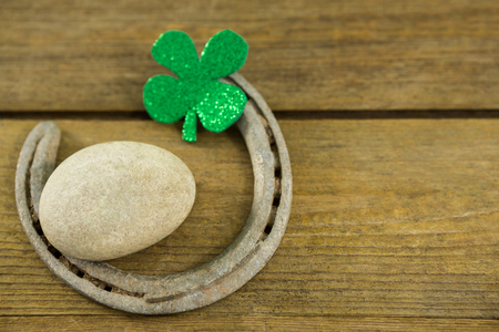 St Patricks Day shamrocks with horseshoe and pebble on wooden surfaceの写真素材