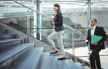 Smiling business executives walking on stairs outside platformの写真素材