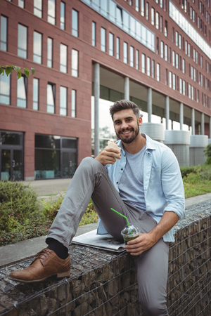 Portrait of smiling executive having veg roll and juiceの写真素材