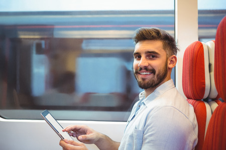 Portrait of smiling executive using digital tablet travelling in train