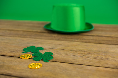 St Patricks Day leprechaun hat with shamrock and gold chocolate coin on wooden backgroundの写真素材