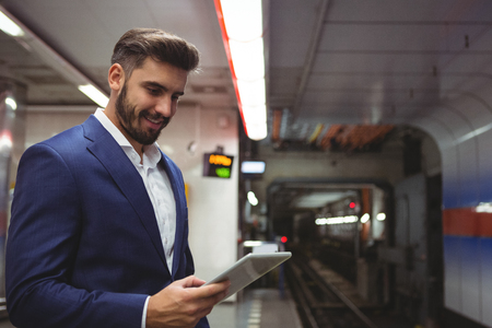 Smiling executive using digital tablet on platformの写真素材