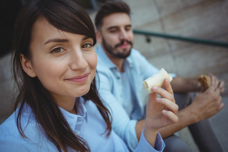 Portrait of smiling executives having breakfast outside office buildingの写真素材