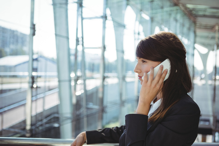 Businesswoman talking on mobile phone at railway stationの写真素材
