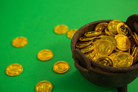 St. Patricks Day pot filled with chocolate gold coins on green background