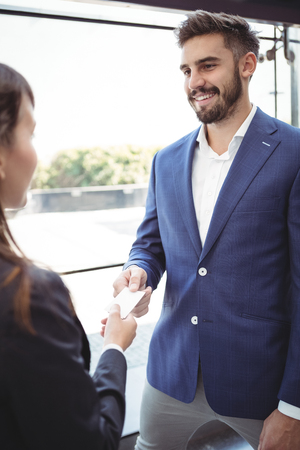 Businesswoman giving visiting card to businessman on platformの写真素材