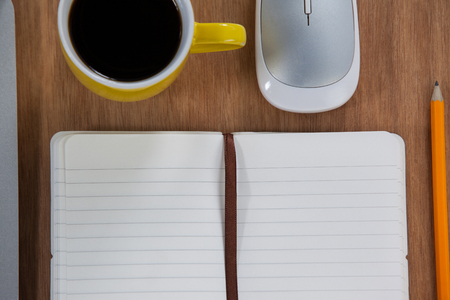 Cup of coffee with laptop, organizer, pencil and mouse arranged on wooden backgroundの写真素材