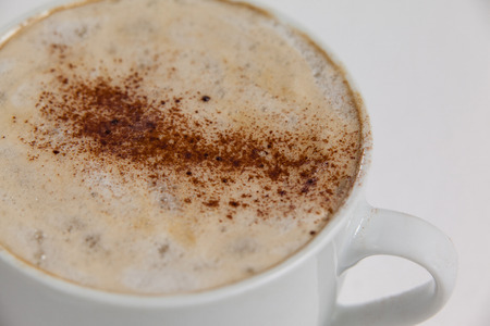 Close-up of white coffee cup with creamy froth on white backgroundの写真素材