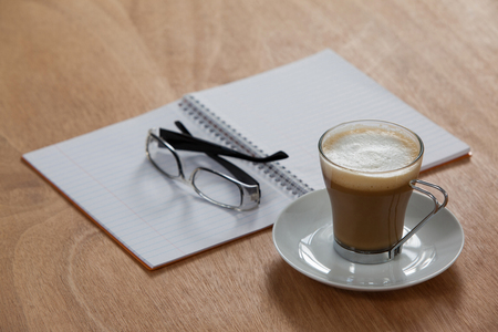 Cup of coffee with spectacles and organizer on wooden backgroundの写真素材