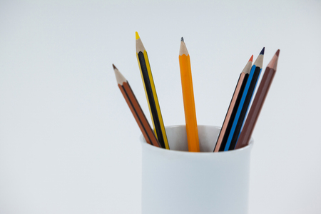 Colored pencils kept in cup on white backgroundの写真素材