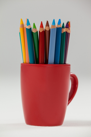 Colored pencils kept in cup on white backgroundの写真素材