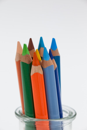 Close-up of colored pencils kept in a glass jar on white backgroundの写真素材