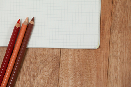 Colored pencils and notebook on wooden backgroundの写真素材