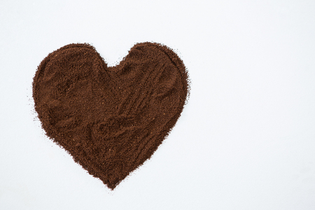 Coffee powder forming heart shape on white backgroundの写真素材