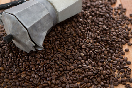 Coffee beans with metallic coffeemaker on wooden table