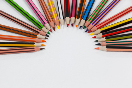 Colored pencils arranged in a semi-circle on white backgroundの写真素材