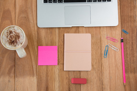Coffee with laptop and various stationeries on wooden tableの写真素材