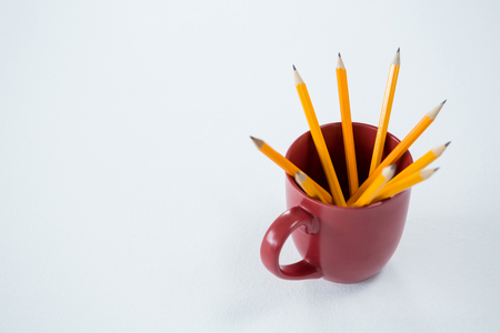 Close-up of yellow color pencils kept in mug on white backgroundの写真素材