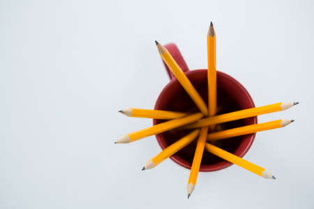 Close-up of yellow color pencils kept in mug on white backgroundの写真素材