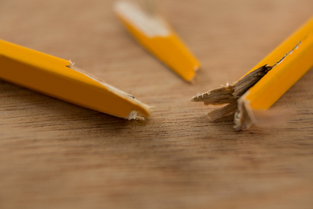 Close-up of broken yellow pencil on wooden backgroundの写真素材