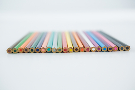 Colored pencils arranged in a row on white backgroundの写真素材