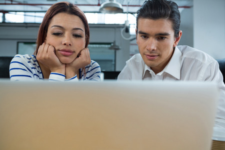 Man and woman working on laptop at desk in creative officeの写真素材
