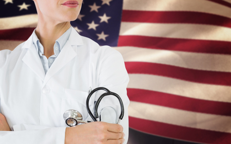 Mid section of a female doctor with stethoscope in hospital against composite image of digitally generated united states national flagの写真素材