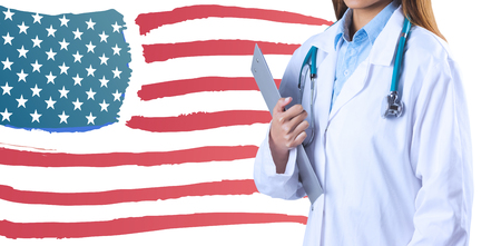 Asian doctor holding clipboard against digitally generated image of american flagの写真素材