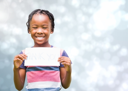 Digital composite of Kid holding a paper smiling against a shining backgroundの写真素材