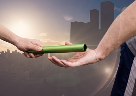 Hand of athlete passing the baton to teammate against digitally composite cityscape backgroundの写真素材
