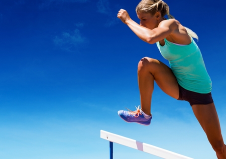 Digital composition of athlete jumping over hurdles against sky in backgroundの写真素材
