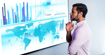 Thoughtful man with finger on chin looking at digital screen at office