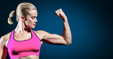 Fitness woman flexing her arms against blue backgroundの写真素材