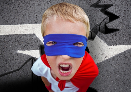 Digital composite of aggressive super boy in red cape and blue mask on roadの写真素材
