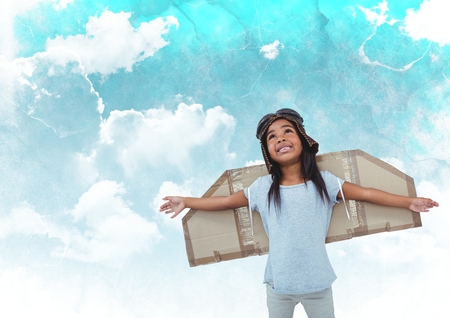 Digital composite image of smiling girl pretending to be a pilot against cloudy sky backgroundの写真素材
