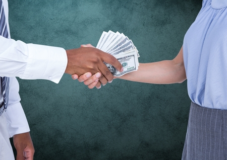 Digital composite image of businessman bribing partner while shaking hands against teal background