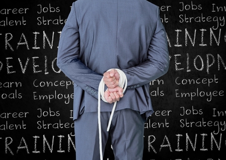 Rear view of businessman with his hands tied with rope against business terms in backgroundの写真素材