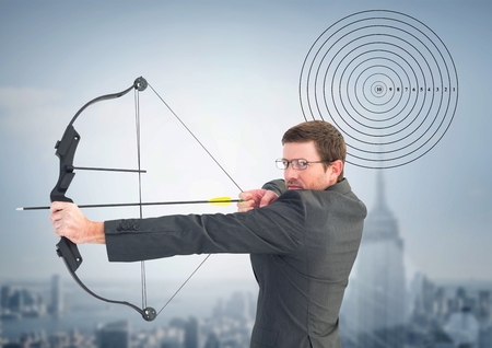 Businessman holding bow and arrow while aiming against cityscape in backgroundの写真素材