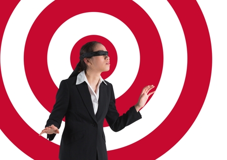 Digital composite conceptual image of businesswoman with black band on eyes against archery boardの写真素材